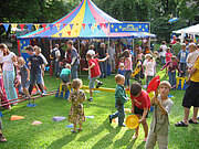 Parkfest mit Zirkuszelt-Pavillon und vielen Familien. Im Vordergrund ein Balance-Parcours.