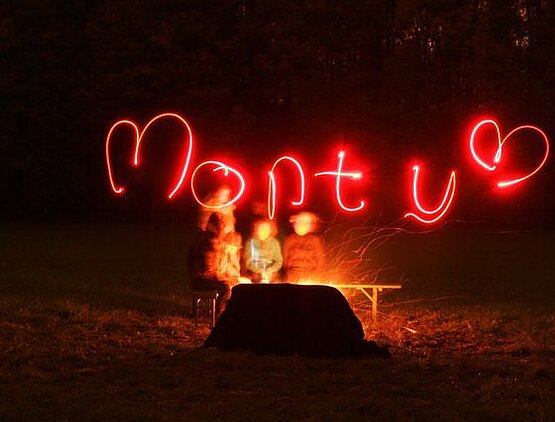Lichtkunstobjekt: Der rote Schriftzug "Monty" schwebt in der dunklen Nachtluft!