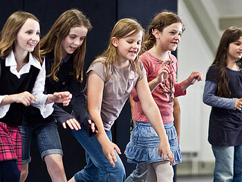 Eine Gruppe Mädchen betritt in Aktion eine Bühne.