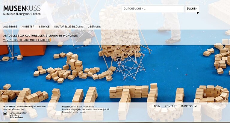 Startbildschirm der Münchner Musenkuss-Seite: Weiße Bauklötze auf blauem Grund