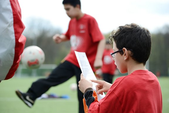 Fußballszene mit zwei Jungs in roten T-Shirts draußen