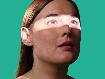 Frau vor grünem Hintergrund, Augenpartie hell beleuchtet