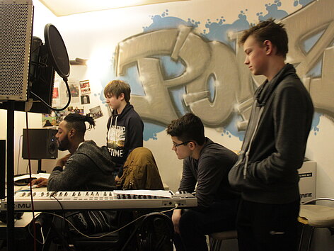Vier Jugendliche arbeiten konzentriert im Tonstudio.