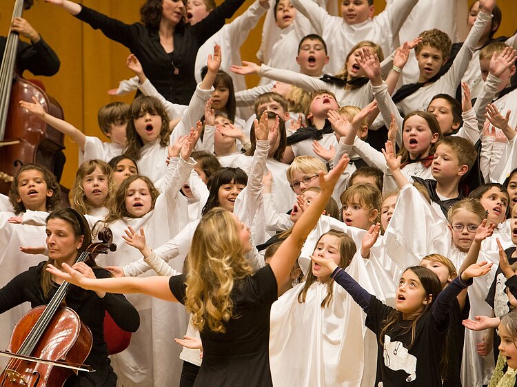 Kinder in weißen Kostümen singen gemeinsam in einem Kinderchor inder Kölner Philharmonie