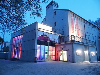 Der bunt angestrahlte Kulturbunker im blauen Abendlicht von außen.