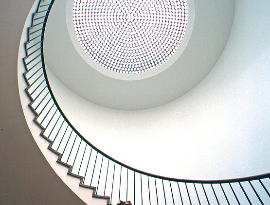 Blick zum kreisförmigen Treppenaufsprung des Museums für angewandte Kunst mit farbiger Brunnenfigur.