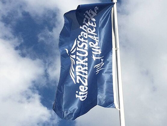 Eine flatternde blaue Fahne mit dem Schriftzug "Kulturarena Zirkusfabrik".