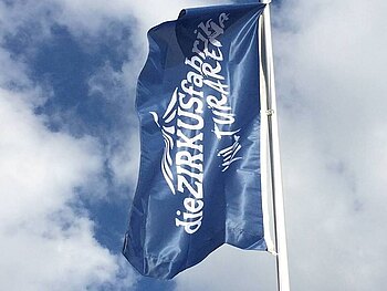 Eine flatternde blaue Fahne mit dem Schriftzug "Kulturarena Zirkusfabrik".