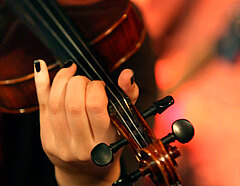 Eine Frauenhand auf dem Griffbrett einer Violine