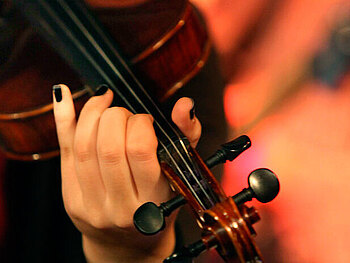 Eine Frauenhand auf dem Griffbrett einer Violine