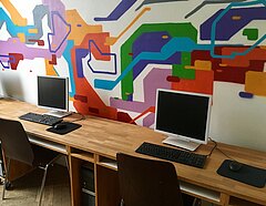 Modern gestalteter Computerraum mit buntem grafischem Wandschmuck.