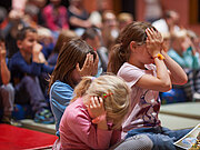Viele Zuschauer-Kinder, sie halten sich Augen und Ohren zu