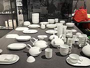 Ein weißes Porzellanservice für etwa 10 Personen ist auf einer hellgrauen Tischplatte aufgestellt.