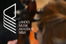 Das Logo der Landesmusikakademie NRW vor einem verschwommenen Orchesterfoto