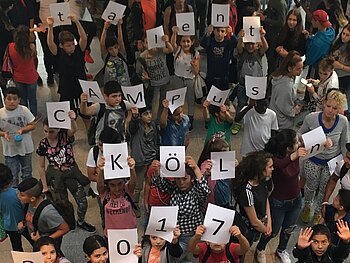 Gruppenbild von oben aufgenommen: etwa 100 Kinder und Teamer halten Buchstaben hoch, die den Begriff talentCAMPus 2017 formen.